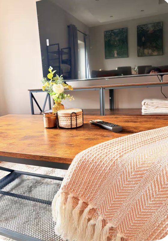 Bedroom with wooden desk, fresh flowers in vase, peach throw blanket, and wall art