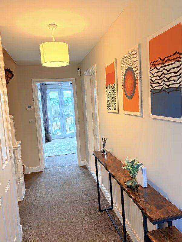 Modern hallway with pendant light, framed abstract wall art, wooden console table and potted plant