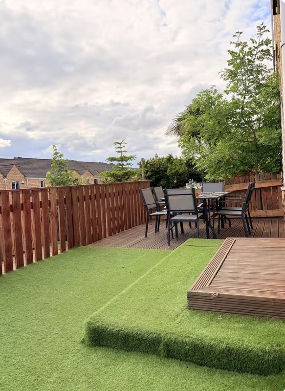 Garden with artificial turf, wooden deck, patio furniture and red fence