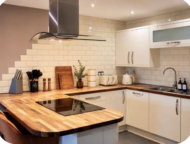 Modern kitchen with white cabinetry, wooden countertops, induction hob and subway tile backsplash