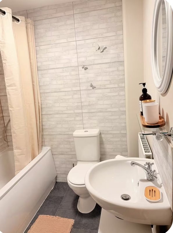 Modern bathroom with white sink, toilet, shower enclosure and tiled walls