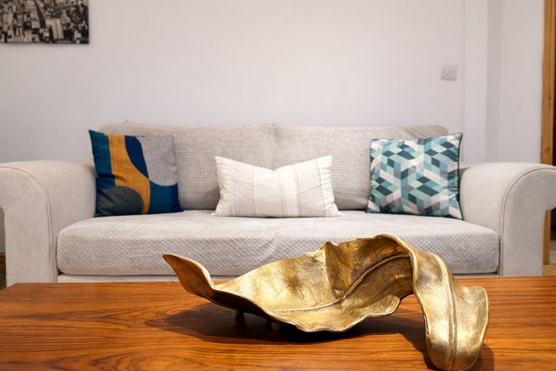 Living room with light gray sofa, decorative cushions, wooden coffee table with gold sculpture