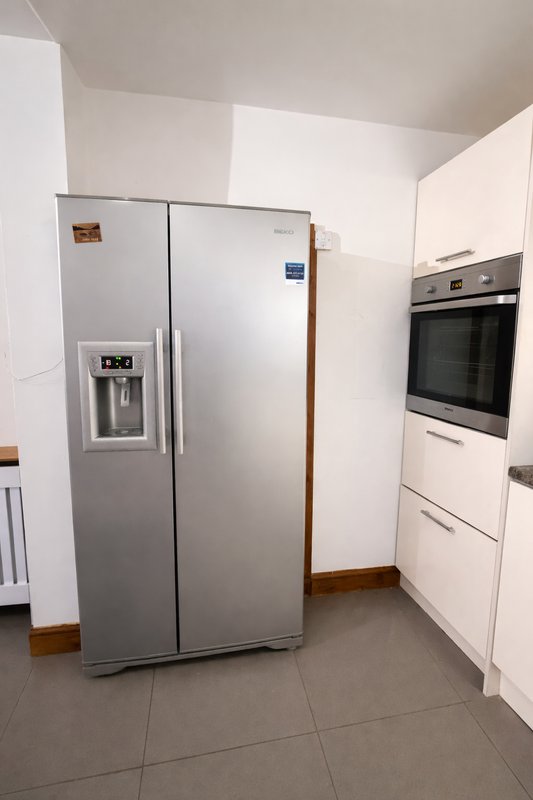 Modern kitchen with stainless steel side-by-side refrigerator, white cabinetry, and built-in oven