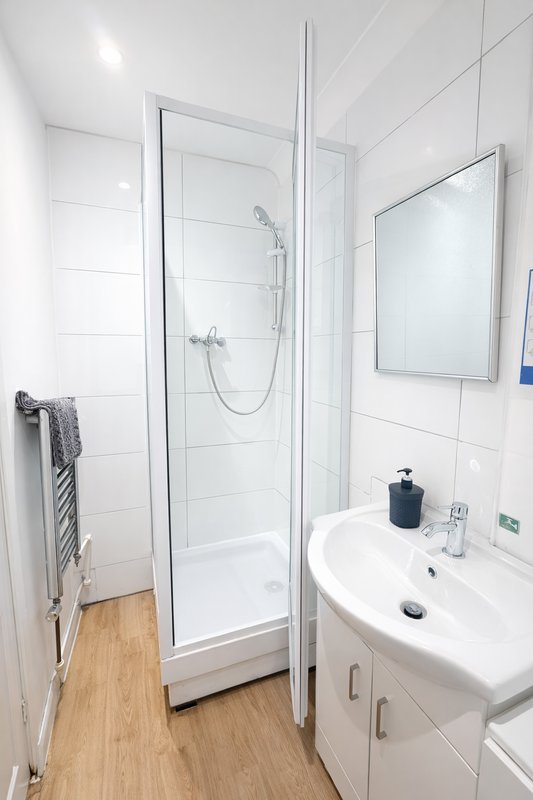 Modern bathroom with white tiles, walk-in shower, sink vanity and mirror