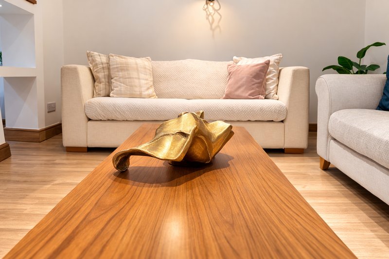 Modern living room with cream sofa, wooden coffee table, gold decorative sculpture, and potted plant
