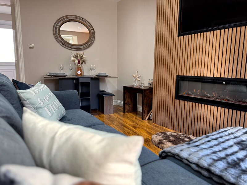 Modern living room with blue sofa, fireplace, wooden flooring and oval mirror