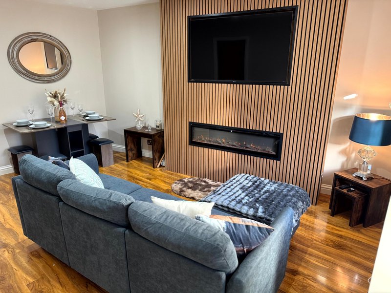 Modern living room with grey sofa, wall-mounted TV, fireplace and wooden flooring