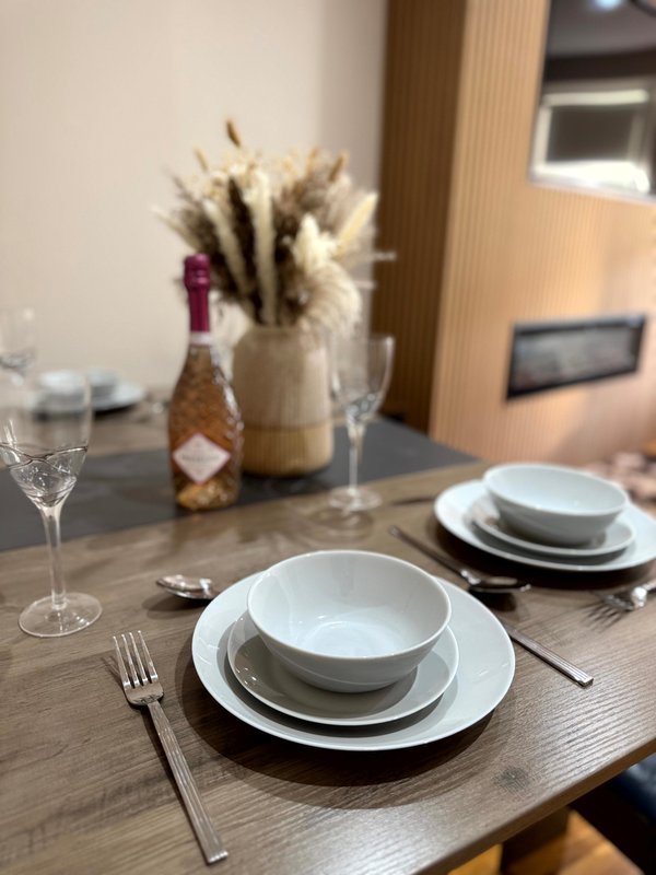 Dining table set with white plates, glassware, cutlery, and floral centerpiece