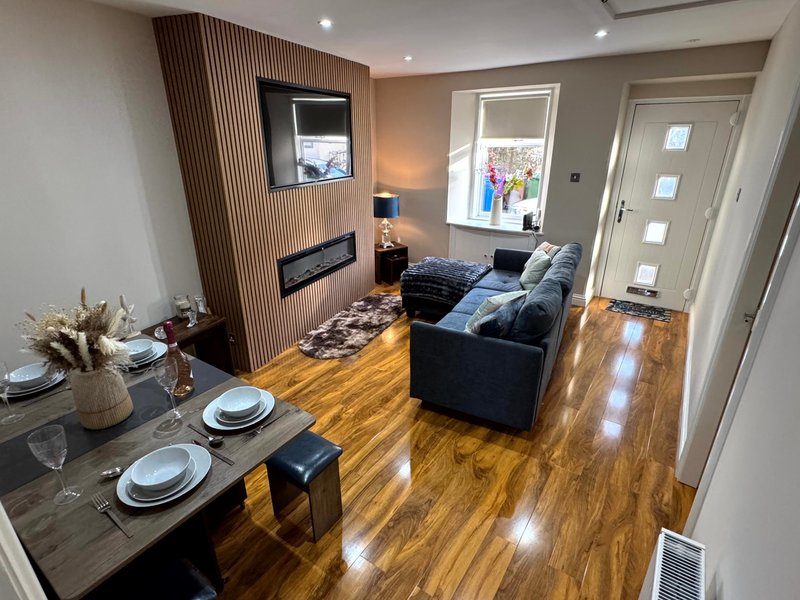 Open-plan living area with dining table, sofa, fireplace, and wooden flooring