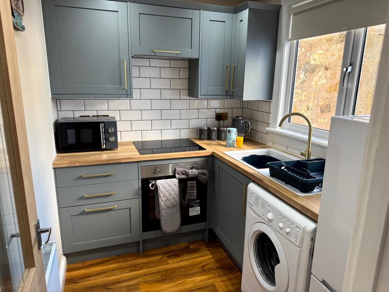 Modern kitchen with gray cabinetry, white subway tile backsplash, wooden countertops, and integrated appliances