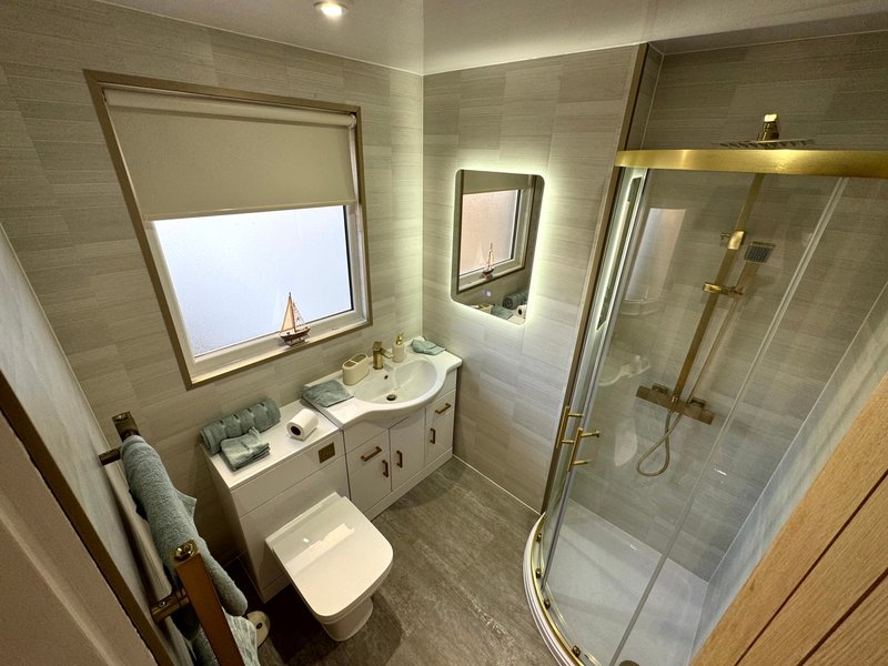Modern bathroom with vanity sink, toilet, walk-in shower and window
