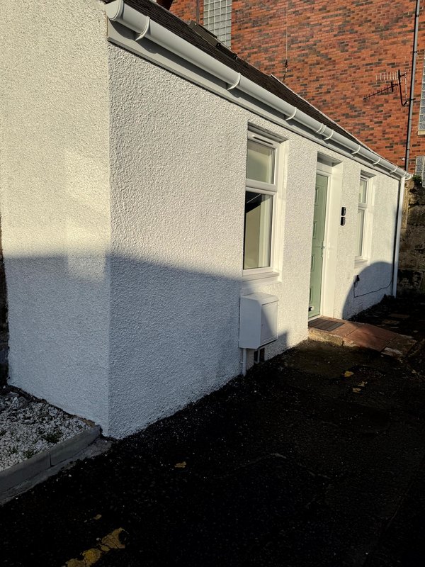 White single-storey extension with window and door, brick building backdrop
