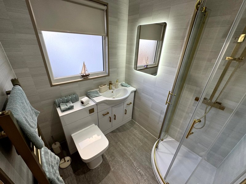 Modern bathroom with vanity sink, toilet, shower enclosure and window overlooking cityscape