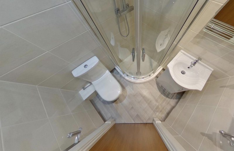 Modern bathroom with toilet, sink, corner shower cubicle and tiled flooring