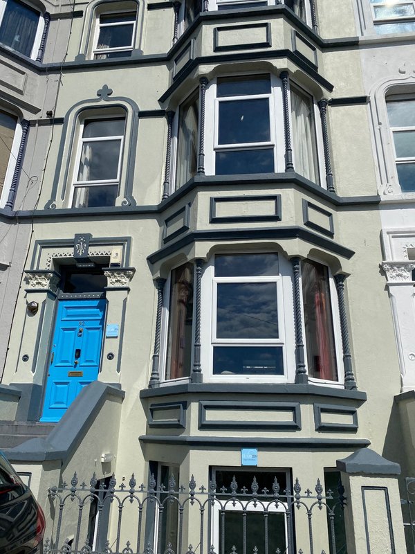 Victorian townhouse exterior with bright blue door, bay windows and ornate stonework