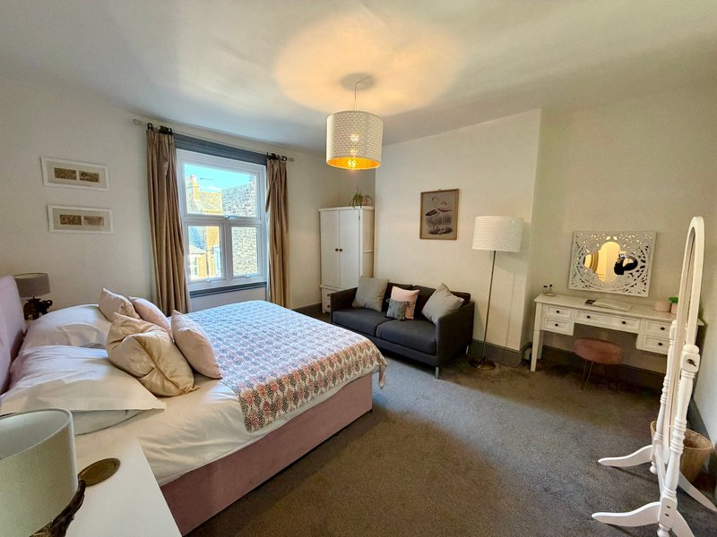 Spacious bedroom with double bed, seating area, desk, pendant light and large window