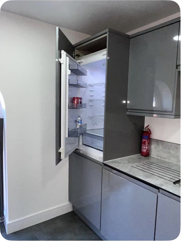 Modern kitchen with open refrigerator, gray cabinetry, and stainless steel worktop