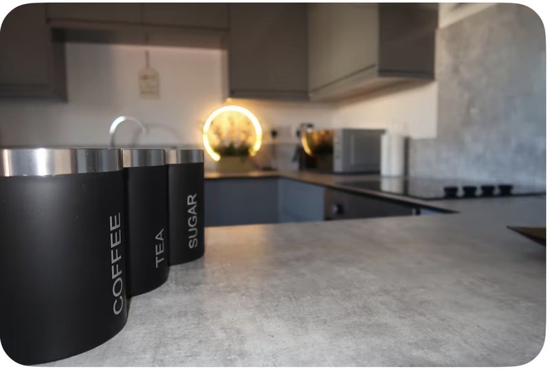 Modern kitchen with black countertop, branded coffee canisters, and pendant lighting