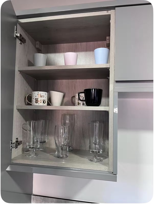 Open kitchen cabinet with shelves displaying mugs, cups, and drinking glasses