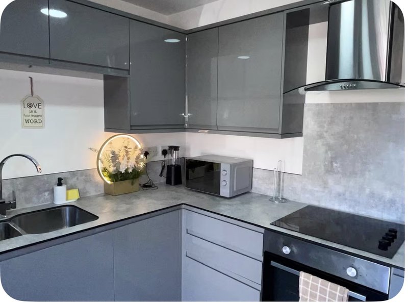 Modern kitchen with grey cabinetry, stainless steel appliances, marble countertops and decorative items