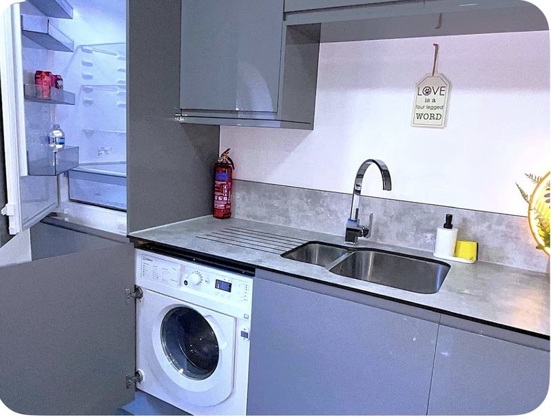 Modern kitchen with washing machine, double sink, gray cabinets and white backsplash