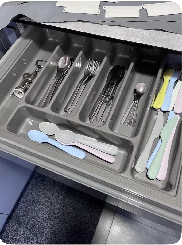 Open kitchen drawer with organized cutlery, utensils and kitchen tools