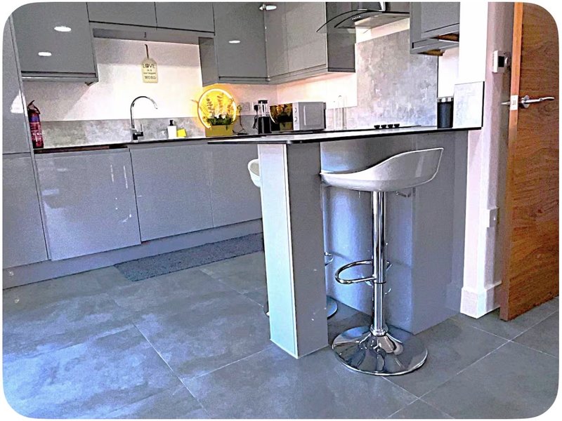 Modern kitchen with gray cabinetry, island seating, stainless steel appliances and concrete flooring