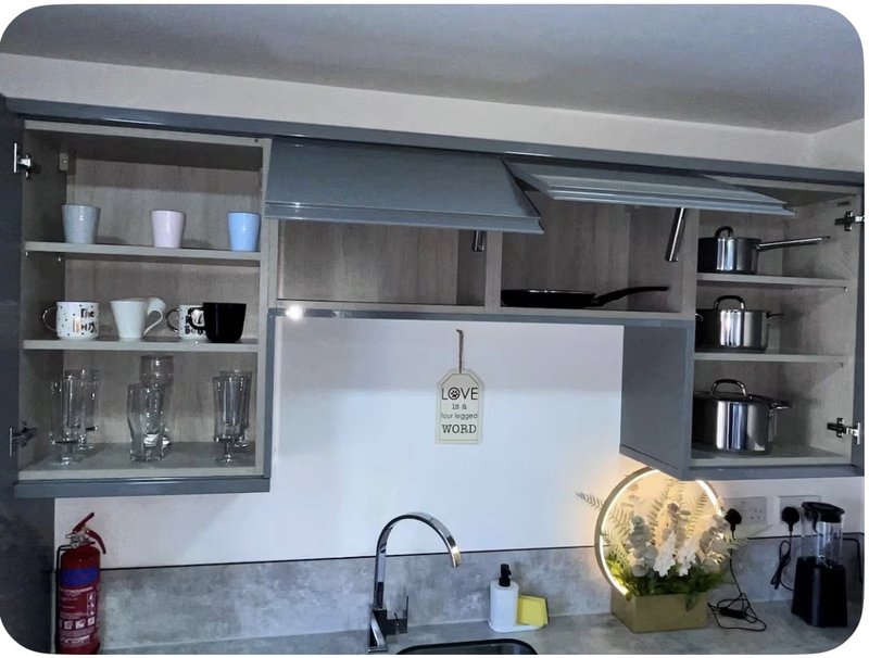 Modern kitchen with gray cabinetry, open shelving, white backsplash, and kitchen accessories