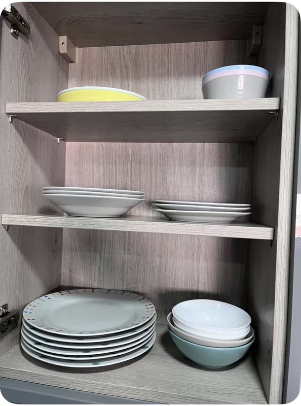 Kitchen cabinet interior with stacked plates, bowls, and food storage containers on shelves