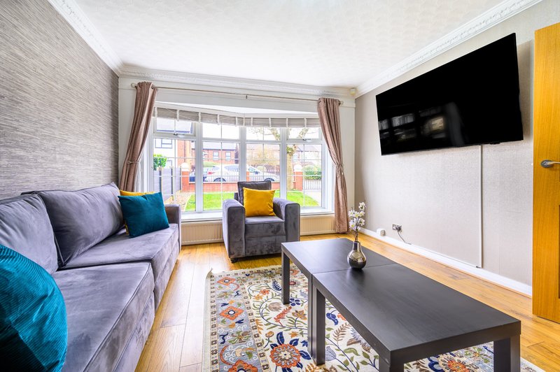 Bright living room with purple sofa, armchair, TV, coffee table and garden view