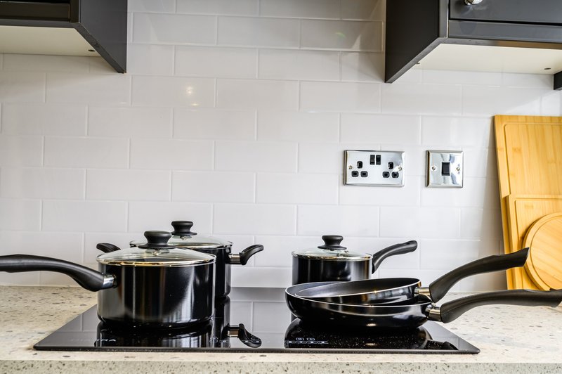 Kitchen counter with black cookware set on stovetop and white subway tile backsplash