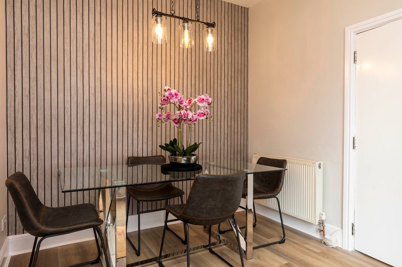 Dining room with black table, chairs, pink flowers, pendant lights and vertical wall paneling