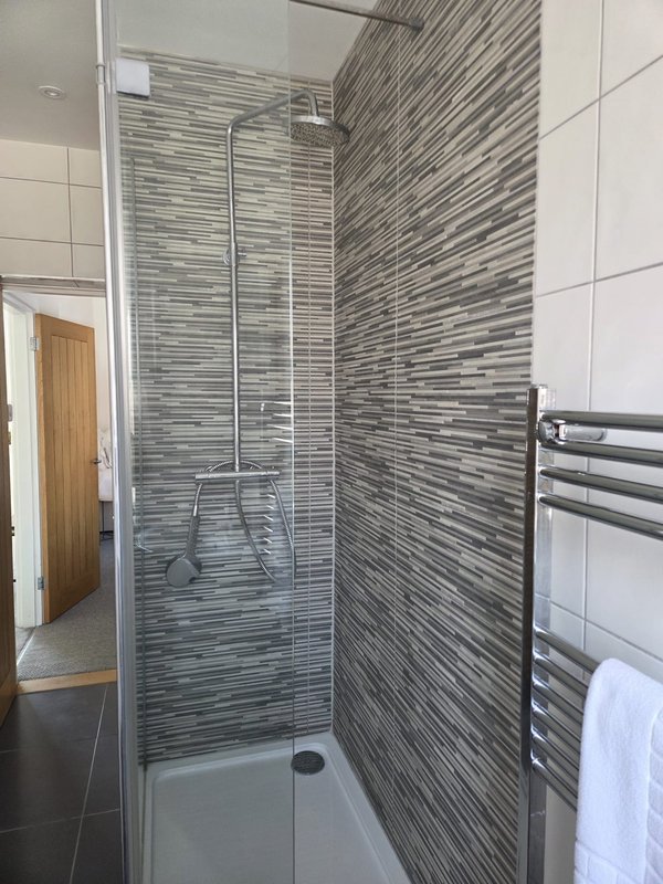 Modern bathroom with walk-in shower, grey striped tiles, towel rail and white towels