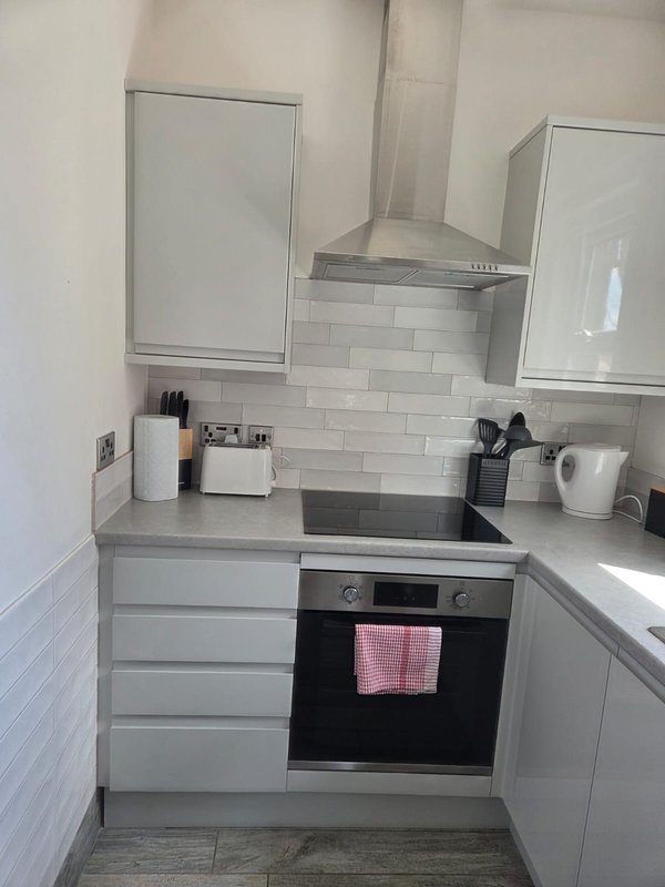 Modern compact kitchen with grey cabinetry, white subway tile backsplash, built-in oven and cooktop