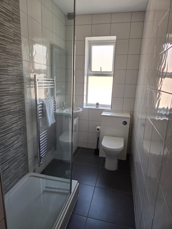Modern bathroom with walk-in shower, toilet, heated towel rail and window