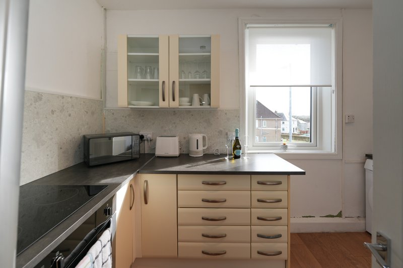 Modern kitchen with cream cabinets, black countertop, and window overlooking street
