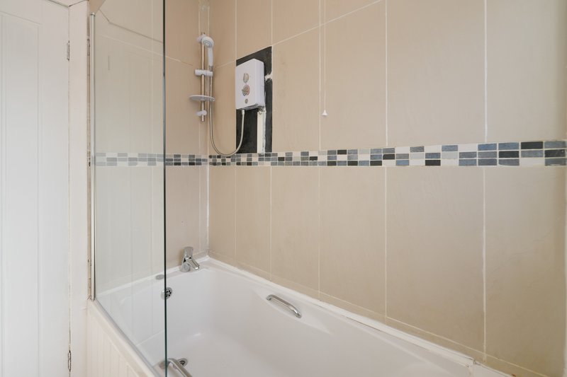 Modern bathroom with bathtub, glass shower screen, beige tile walls and chrome fixtures