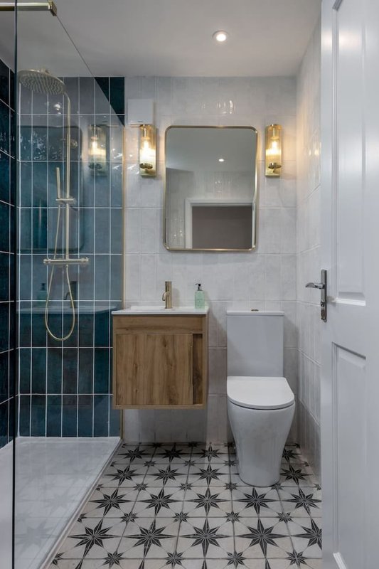 Modern bathroom with walk-in shower, wooden vanity, mirror, and patterned tile flooring