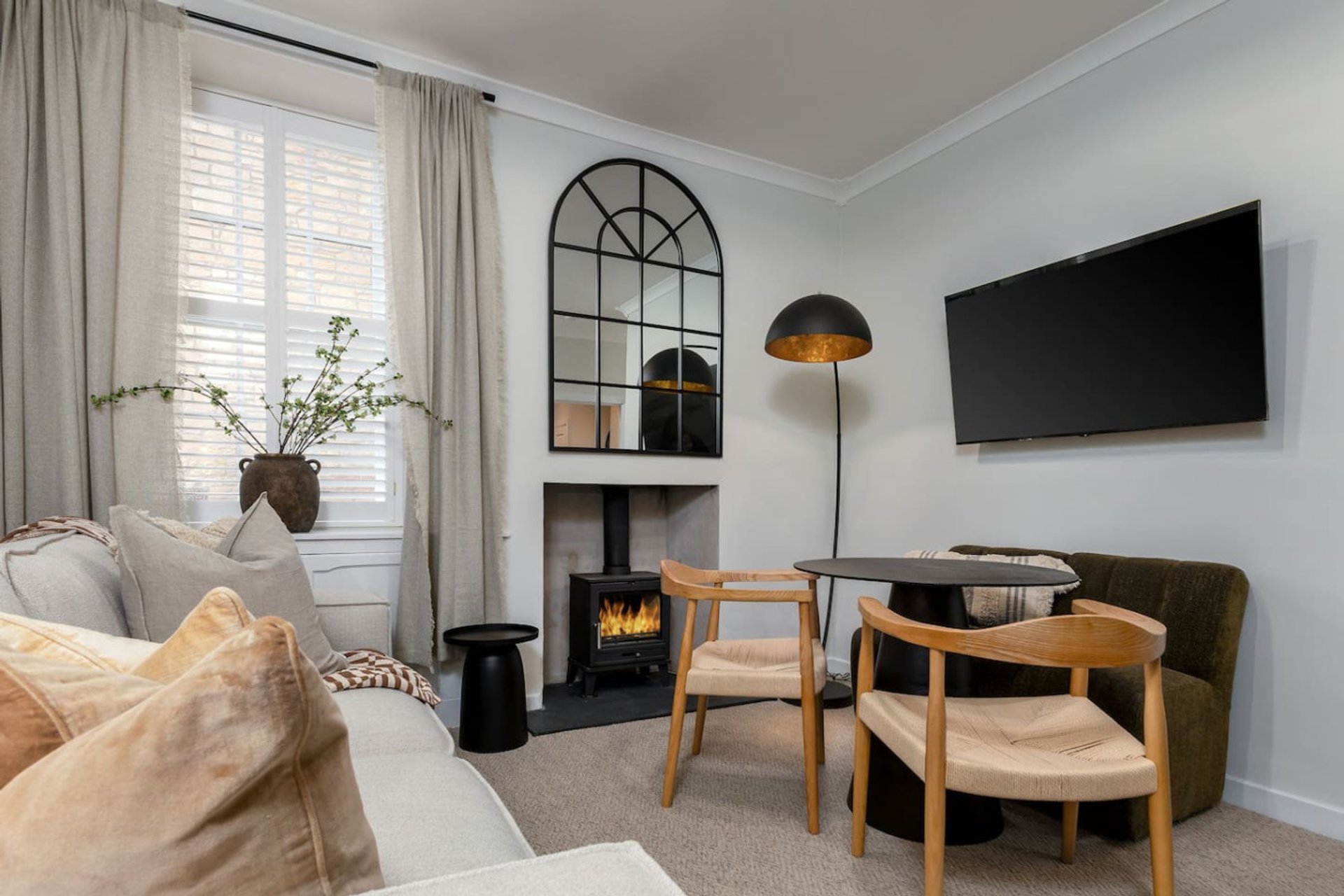 Modern living room with fireplace, seating area, TV, and large arched mirror
