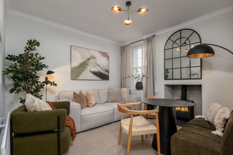Modern living room with green armchair, gray sofa, fireplace, and wood dining chair