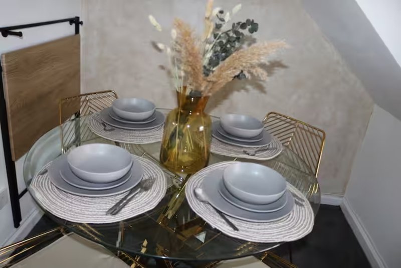 Dining table set for four with white plates, patterned placemats and dried flowers