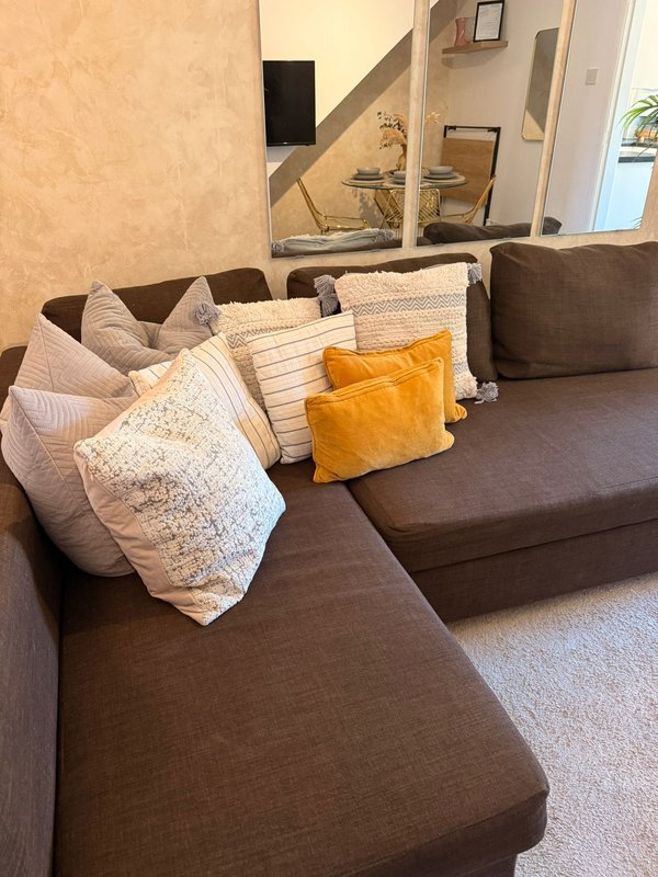 Brown modular sofa with decorative cushions and throws in neutral and yellow tones