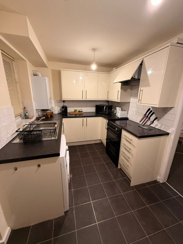 Modern kitchen with cream cabinets, black countertops, black tile floor and stainless steel appliances