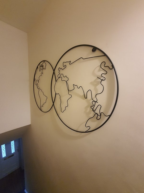 Wall-mounted wire art depicting world maps and continents in minimalist design