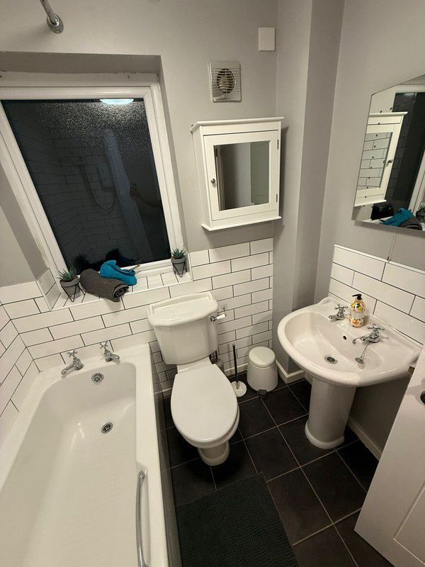 Modern bathroom with white subway tile, dark floor, dual sinks, toilet and shower enclosure