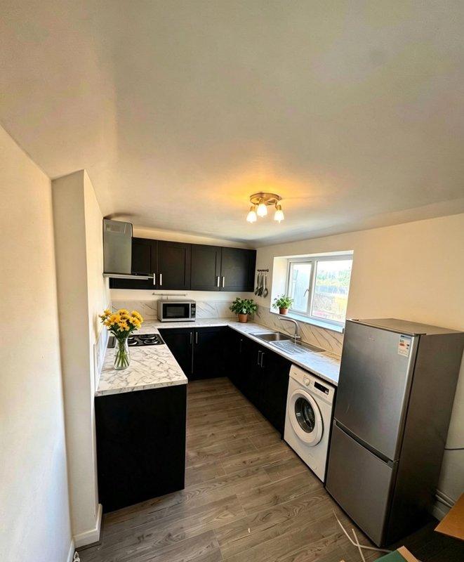 Modern kitchen with black cabinetry, white countertops, stainless steel appliances and natural light