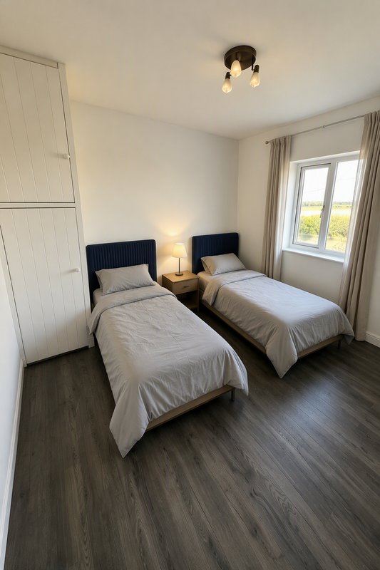 Twin bedroom with two single beds, dark wood flooring, wardrobe and window with curtains