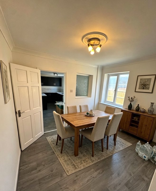 Dining room with wooden table, upholstered chairs, and ceiling light fixture