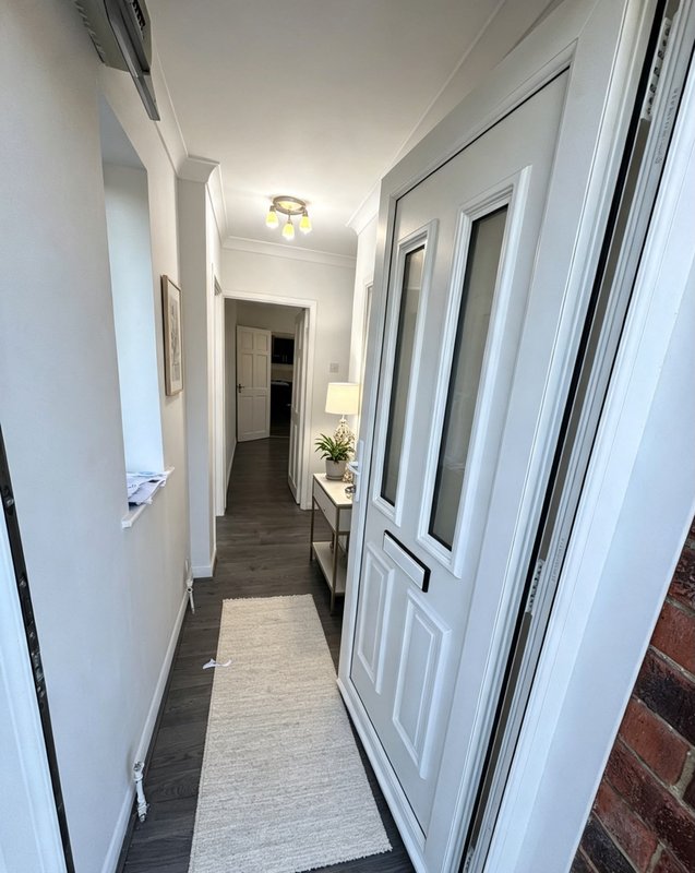 Long hallway with white walls, dark flooring, ceiling light and multiple white doors