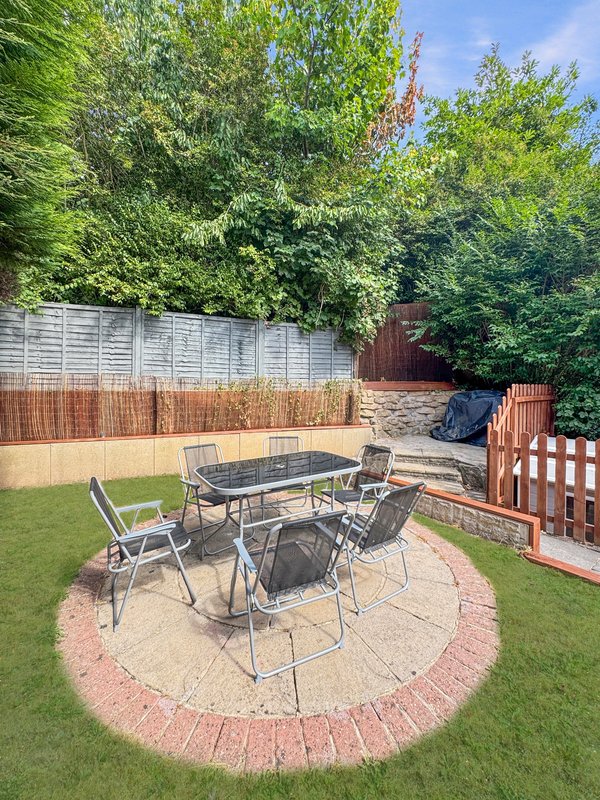 Garden patio with dining table, chairs, lawn, fencing and mature trees